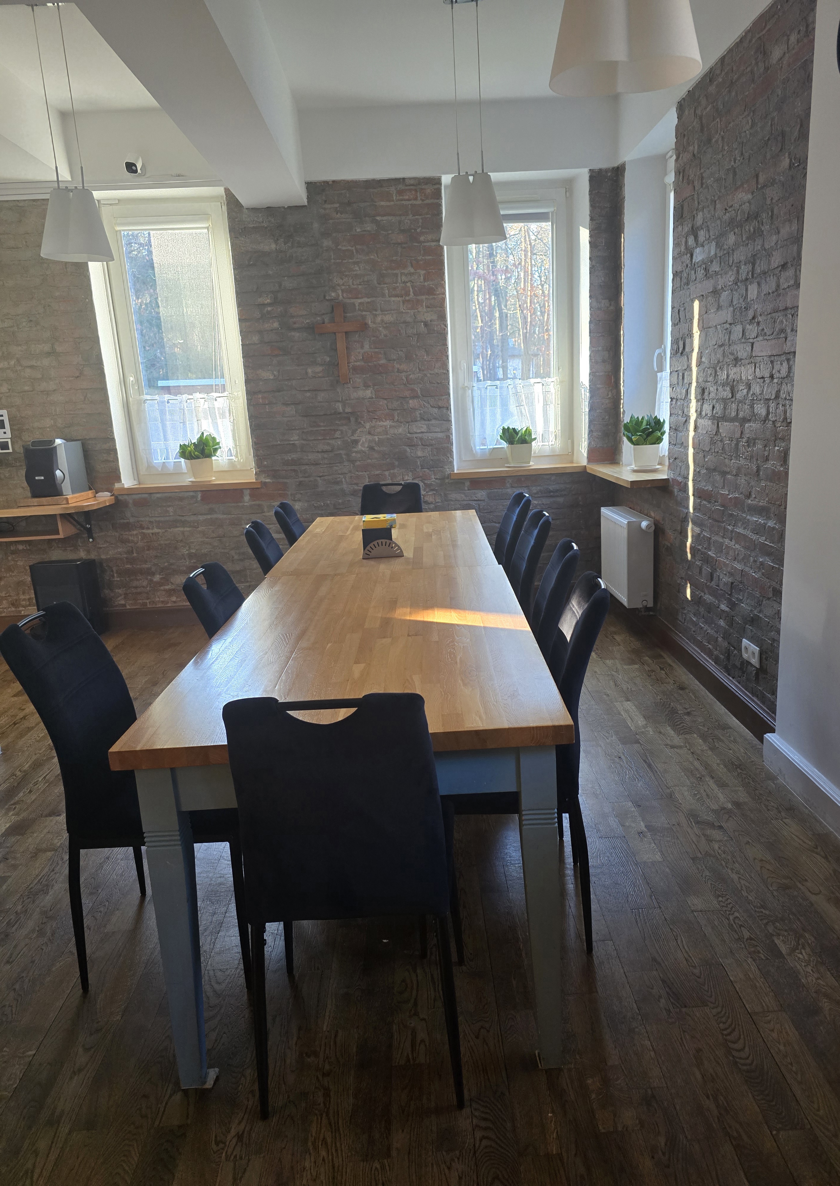 Duży stół z dwunastoma miejscami w sali głównej Domu Dolańskiego, przez duże okna do środka pomieszczenia wlewa się bystre poranne światło